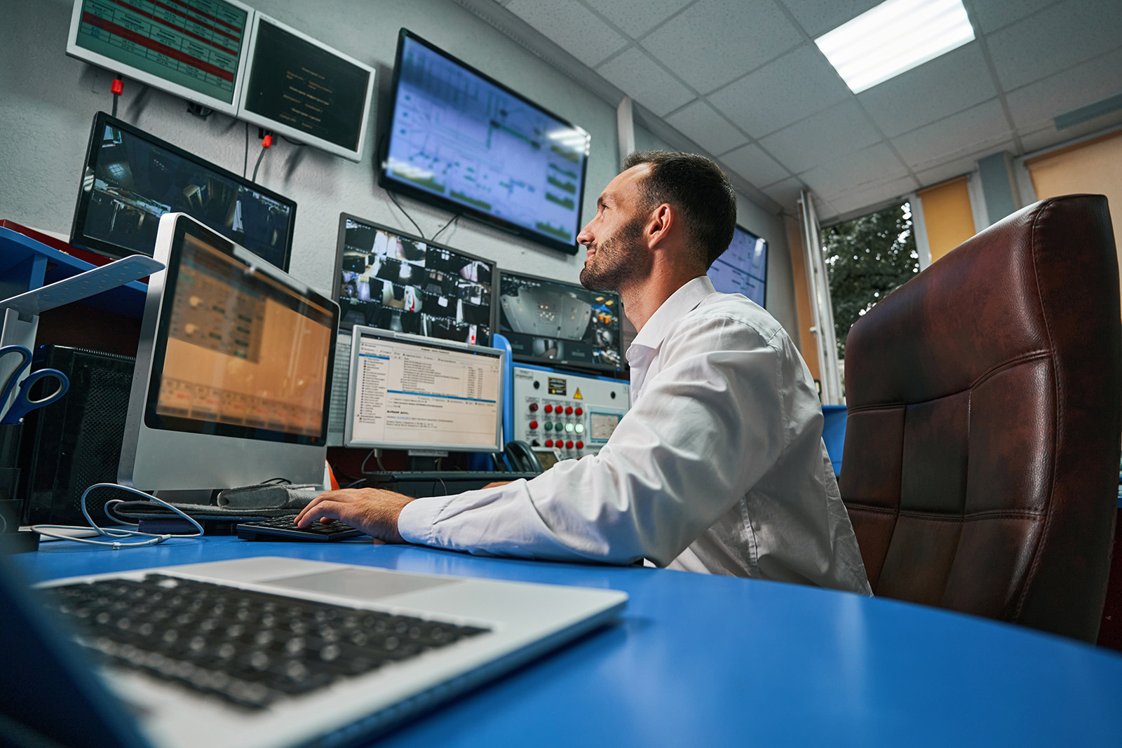 Data centre technician at computer watching camera image on screen