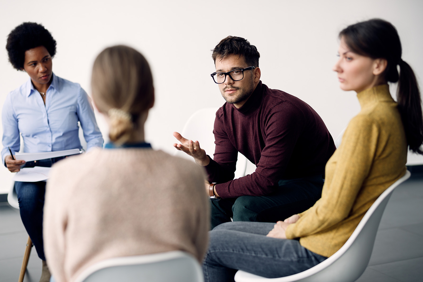 Young man talking while attending group therapy at medical centre.